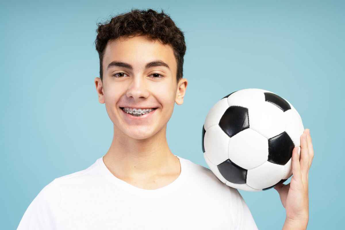 boy wearing braces holding football sports