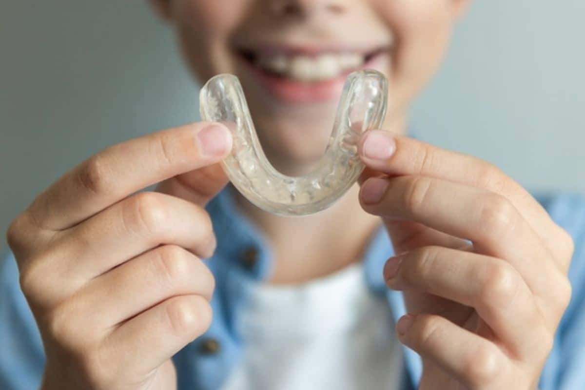 smiling kid holding invisalign clear aligner