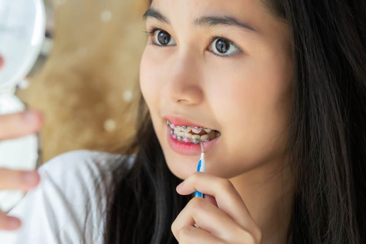 lady cleaning braces to maintain oral health